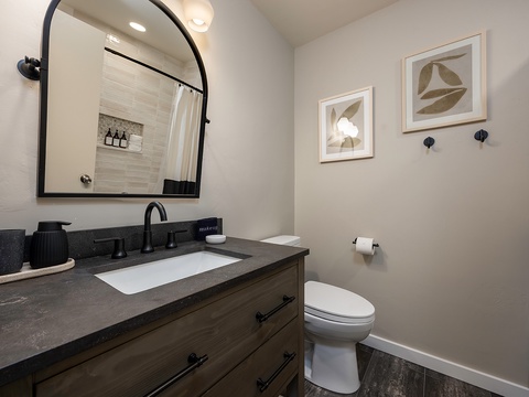 Freshen up in your modern bathroom featuring a sleek vanity with dark countertops, clean lines, and coastal-inspired decor. The separate tiled shower awaits after your day exploring.