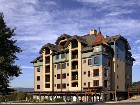 A distinctive alpine-style vacation property with a charming turret and mountain-resort architecture, located in a scenic area with forested hills visible in the distance.