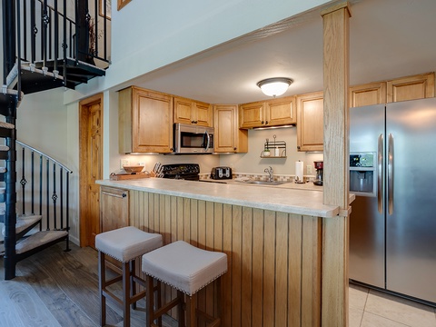 Your fully-equipped kitchen features warm wood cabinetry, stainless appliances, and a breakfast bar perfect for morning coffee or quick meals together.