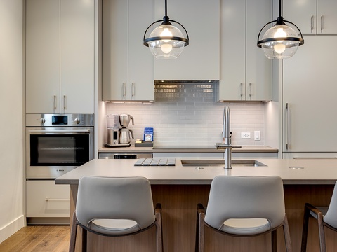 Your modern, fully-equipped kitchen awaits with sleek appliances, stylish pendant lighting, and an inviting breakfast bar perfect for morning coffee or casual meals.
