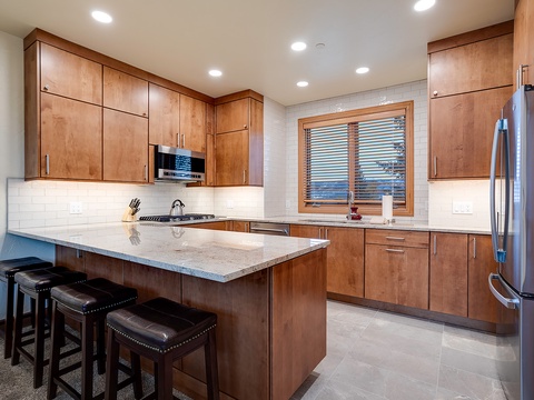 Your fully equipped kitchen features sleek granite countertops, stainless steel appliances, and a spacious island with seating—perfect for cooking and gathering together.