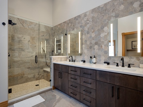 Step into this spa-inspired bathroom featuring a spacious walk-in shower, dual vanities with elegant lighting, and modern hexagonal tile accents. This luxurious retreat combines style with comfort for your ultimate relaxation.