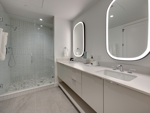 Step into your spa-like bathroom where crisp, clean lines meet relaxation—imagine refreshing morning showers in the sleek glass enclosure and your evening wind-down routine at the spacious double vanity.