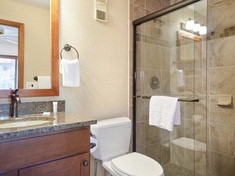 Refresh in your tastefully updated bathroom with plush towels, a granite vanity, and a walk-in glass shower lined with warm neutral tile.
