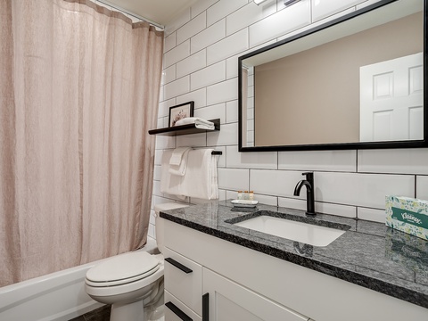 Step into your private sanctuary with crisp white subway tiles, sleek granite countertops, and modern matte black fixtures. Plush towels and thoughtful touches await your arrival.