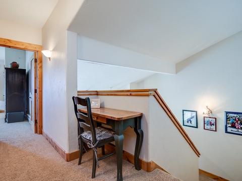 A cozy workspace awaits you upstairs with charming woodwork, soft lighting, and family photos—perfect for catching up on emails or jotting down your vacation memories.