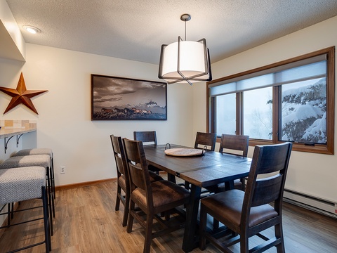 Gather around this inviting dining table where you'll share memorable meals with loved ones while enjoying natural light and serene winter views through the large windows.