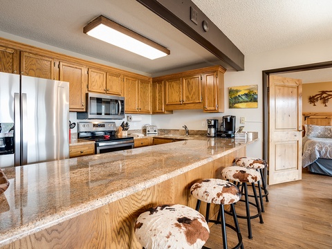 Your spacious kitchen features gleaming granite countertops, stainless steel appliances, and a breakfast bar with cowhide stools perfect for morning coffee or casual meals.
