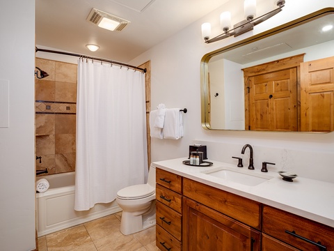 Step into your elegantly appointed bathroom with warm wood vanity, pristine white countertops, and a soothing tiled shower—everything you need to refresh after a day of adventure.