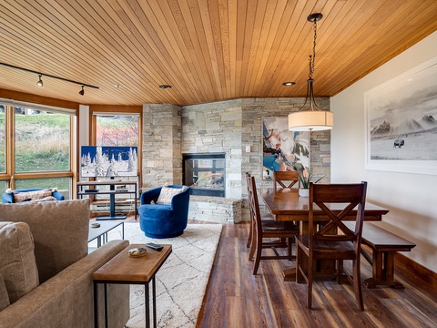 Step into your cozy mountain retreat where warm wood tones and stone fireplace create the perfect gathering space. Relax in plush seating while natural light streams through expansive windows framing serene views.