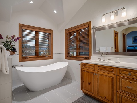 Sink into the freestanding tub after a long day, where natural light filters through wooden blinds and creates your own private spa retreat.