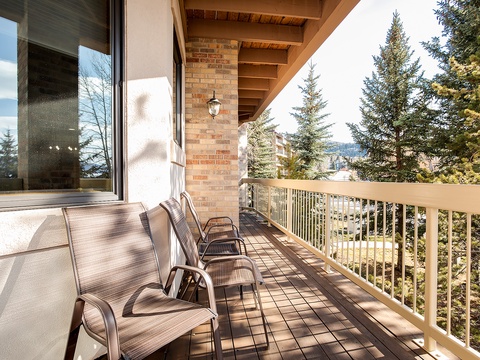 Step onto your private balcony and breathe in crisp mountain air as sunlight streams across comfortable lounge chairs overlooking towering pines and distant peaks.