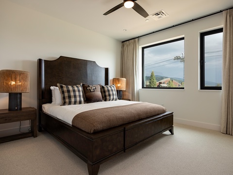 Wake up to mountain scenery framed by large windows in your peaceful bedroom retreat. The plush bed and warm tones create the perfect sanctuary for restful nights.