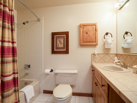 Your private bathroom offers everything you need to refresh and recharge: a tiled shower-tub combo, spacious vanity with storage, and fluffy white towels ready for your arrival.