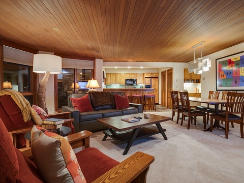 Your mountain retreat awaits with warm wood ceilings, plush seating around the fireplace, a fully-equipped kitchen, and a dining table perfect for gathering after your adventures.