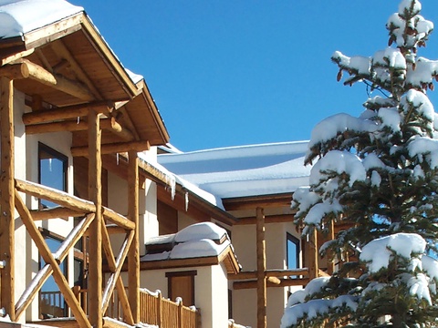 Snow-covered alpine lodge with frosted evergreen and bright blue skies sets the scene for a perfect winter mountain escape.