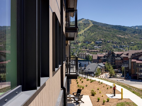 The property sits in a mountain community with residential buildings and forested slopes visible in the surrounding area.