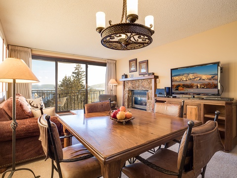 Settle into your cozy retreat with stunning mountain views through expansive balcony doors. Gather around the dining table, warm up by the fireplace, and enjoy home entertainment in this inviting space.