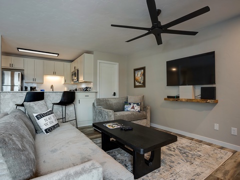 This open-concept living space offers a cozy retreat where you can unwind on plush seating after preparing meals in the modern, fully equipped kitchen just steps away.