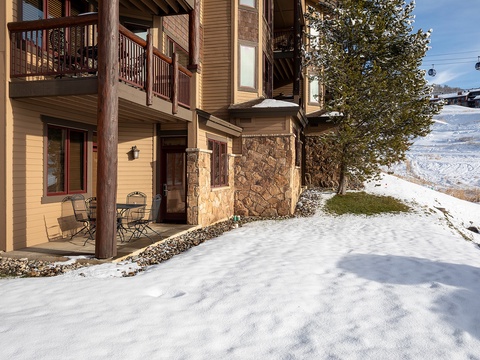 This mountain property features stone accents and multi-level balconies, positioned near ski slopes with gondola access visible in the backdrop. Private patios offer easy outdoor access.