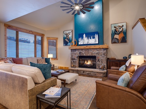 Sink into plush seating by the crackling stone fireplace, where natural light pours through large windows and mountain-inspired artwork creates your perfect après-ski retreat.