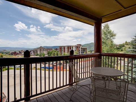 Covered balcony overlooking distant mountains and resort buildings set among mature evergreens—part of the surrounding neighborhood.