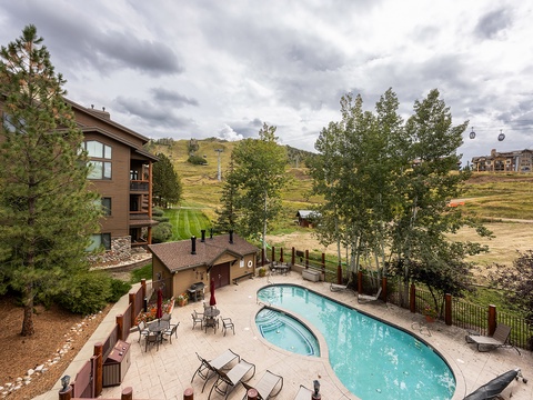 Nestled in a scenic mountain setting, the property features an inviting pool and patio area surrounded by trees, ski slopes, and natural beauty for a peaceful getaway.