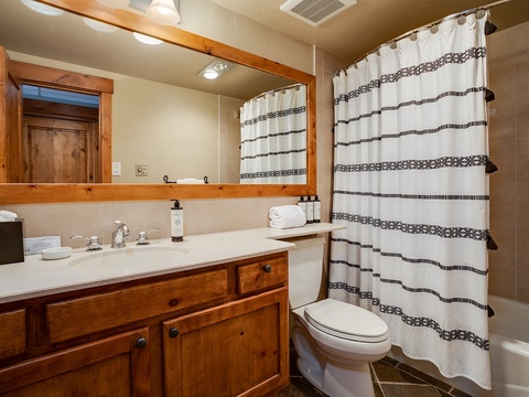 Your private bathroom features warm wood accents, a full tub-shower combo, and plush towels—everything you need to feel refreshed and at home during your mountain getaway.