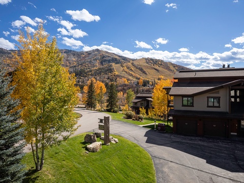 Modern mountain retreat featuring vibrant autumn foliage, ski slope views, and convenient parking, nestled in a peaceful neighborhood beneath dramatic peaks.