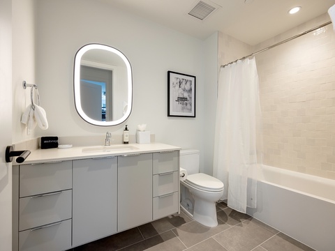 Step into your modern, spa-inspired bathroom where a backlit mirror and crisp white subway tiles create a serene retreat. Unwind in the soaking tub or freshen up at the sleek vanity—your personal sanctuary awaits.
