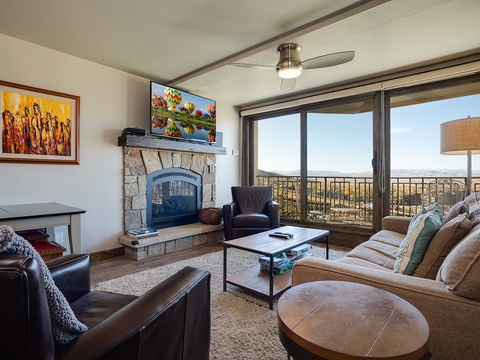 Sink into plush seating and enjoy sweeping vistas through floor-to-ceiling glass doors. Your living room features a cozy stone fireplace, modern entertainment, and a private balcony where stunning valley views await.
