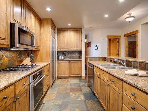 Picture yourself preparing meals in this spacious, fully equipped kitchen, where warm wood cabinetry, granite countertops, and modern appliances invite your culinary creativity throughout your stay.
