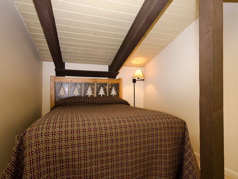 Drift off under charming exposed beams in this cozy bedroom, where rustic wood accents and soft lighting create your perfect mountain retreat.