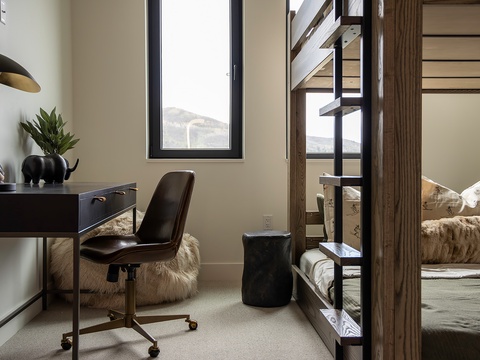 Your cozy retreat features a bunk setup with mountain views, a stylish workspace with sleek lighting, and thoughtful decor touches—perfect for unwinding after a day of adventure.