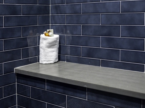 A sleek bench and fluffy towel await in your stylish tiled shower, where modern design meets your everyday comfort.