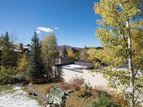 This mountain retreat is nestled among golden aspens and evergreens, offering a serene seasonal setting with nearby peaks as a backdrop.