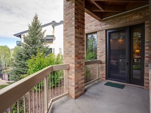 Brick and wood details frame the private entry, surrounded by lush trees and landscaped gardens offering a peaceful, secluded arrival experience.