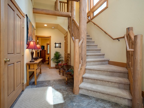 Step into your private mountain retreat with this inviting entryway featuring beautiful natural wood accents and warm lighting. The carpeted staircase leads to your upstairs haven, while the thoughtfully designed space welcomes you home after a day of adve