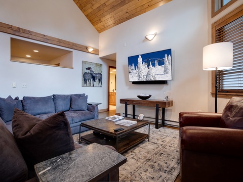 Sink into plush seating in your mountain-modern living room, where vaulted wood ceilings and thoughtful design create the perfect retreat after an adventure-filled day.