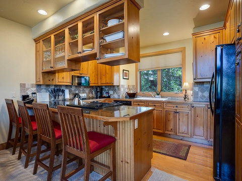 Gather around the island in your spacious, fully-equipped kitchen with warm wood cabinetry, modern appliances, and plenty of room to cook and create memories together.