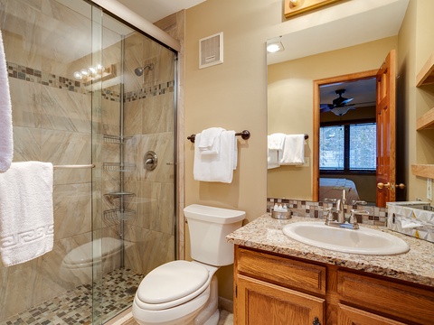 Your private bathroom offers a spacious walk-in shower with elegant tilework, plush towels, and a granite vanity where you can freshen up after your mountain adventures.