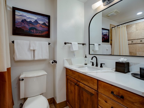Step into your beautifully appointed bathroom with warm wood vanity, elegant marble countertops, and crisp white towels ready for you. Enjoy the cozy mountain artwork and thoughtful touches that make this space feel like home.
