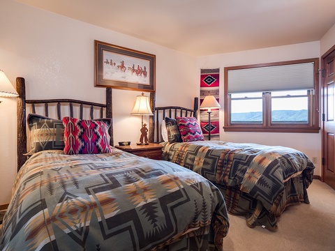 Drift off in cozy twin beds with rustic charm and mountain views framing your mornings. Vibrant textiles and warm wood accents bring a welcoming, home-away-from-home feel.