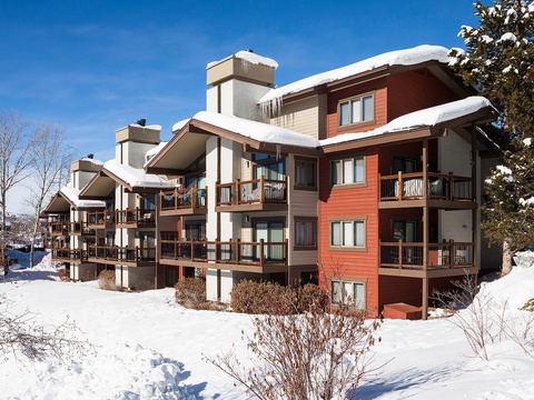 This multi-unit mountain property features spacious balconies and modern alpine architecture set against a pristine winter landscape, perfect for ski season getaways.