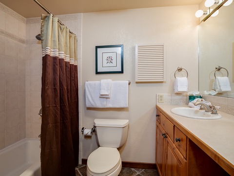 Your private bathroom offers a full tub-shower combo, fresh towels, and wood vanity with ample counter space for your comfort and convenience.