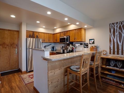 Gather around the breakfast bar in your fully equipped kitchen, where warm wood tones and granite counters create the perfect space to start your mountain mornings together.