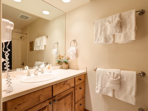 Step into your private bathroom, where crisp white linens await and soft lighting creates a warm, spa-like atmosphere for unwinding after your adventures.