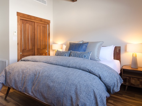 Drift off in this serene bedroom featuring a plush bed with soft linens, warm bedside lighting, and rustic wood accents that create a cozy retreat for your getaway.