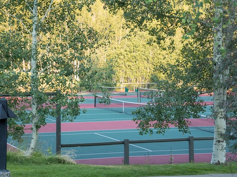 Tennis courts framed by golden aspens offer a scenic setting for active recreation near the property.