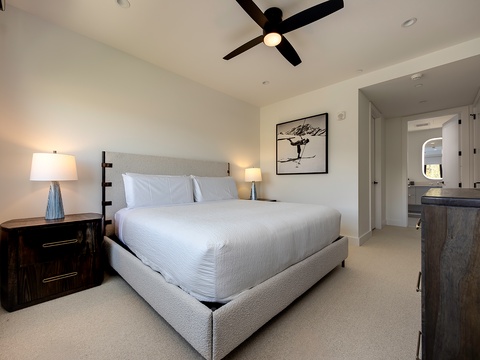 Your serene bedroom retreat features a plush king bed with crisp white linens, contemporary furnishings, and sleek ceiling fan keeping the space cool and comfortable.
